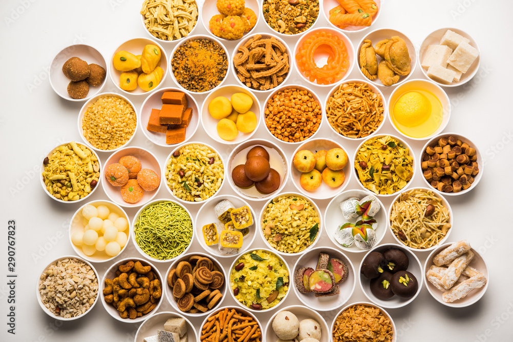 Rangoli of sweets and Farsan/snacks in bowls for Diwali with diya over white background Rangoli of sweets and Farsan/snacks in bowls for Diwali with diya over white background