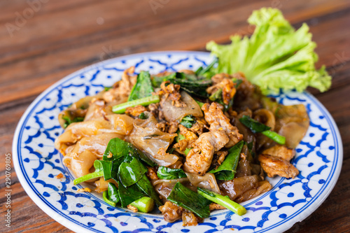 Fried Noodle in Soy Sauce in beautiful dish on wooden table, special Thai food in Thailand