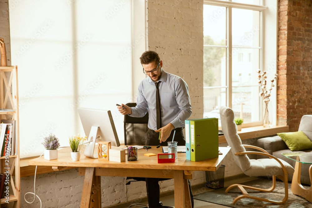 Management. A young businessman moving in the office, getting new work place. Young male office worker while managing after promotion. Looks happy. Business, lifestyle, new life concept. Unpacking. Management. A young businessman moving in the office, getting new work place. Young male office worker while managing after promotion. Looks happy. Business, lifestyle, new life concept. Unpacking.