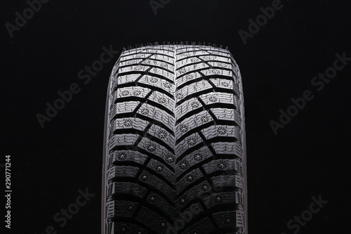 new winter studded tire closeup on black background. a lot of spikes, driving safety in winter on ice, new.
