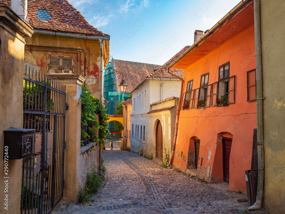 Stone paved medieval streets with colorful houses in Sighisoara, Transylvania region, Romania.