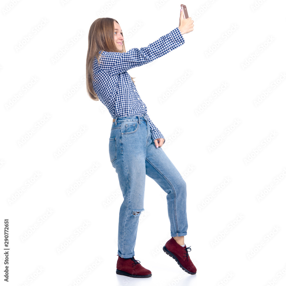 Woman in jeans and blue shirt smiling standing making selfie smartphone on white background isolation Woman in jeans and blue shirt smiling standing making selfie smartphone on white background isolation