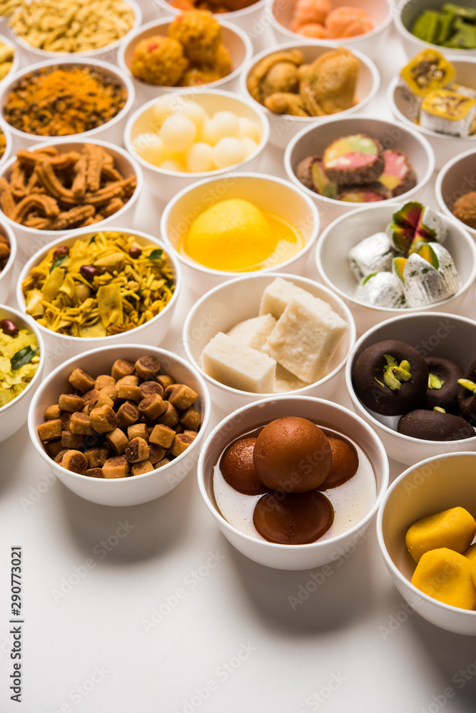 Rangoli of sweets and Farsan/snacks in bowls for Diwali with diya over white background Rangoli of sweets and Farsan/snacks in bowls for Diwali with diya over white background