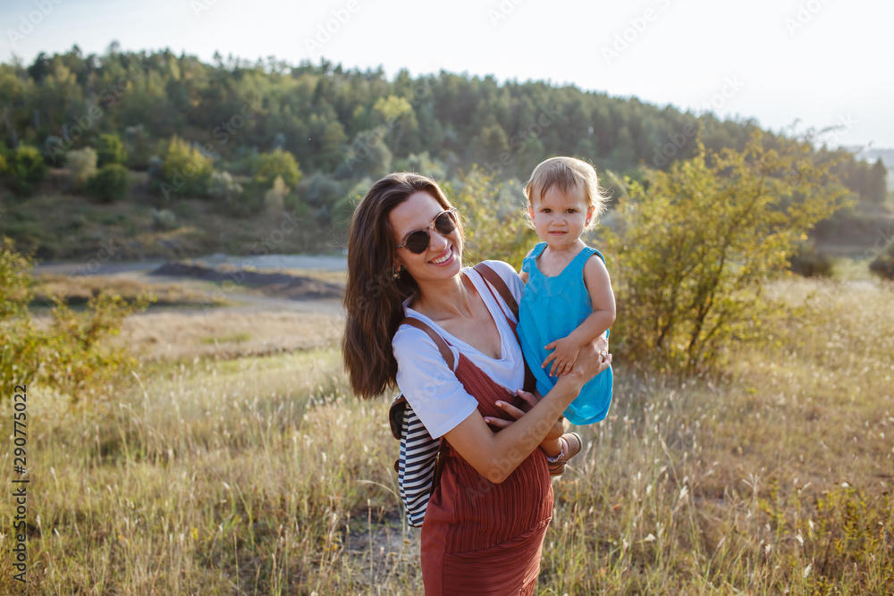 Happy mother and daughter on a green field at sunset. Happy mother and daughter on a green field at sunset.
