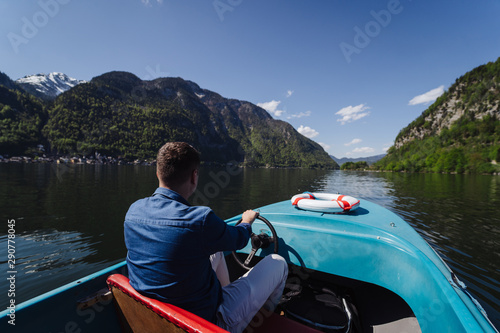 Handsome young guy controls a motorboat on a mountain lake