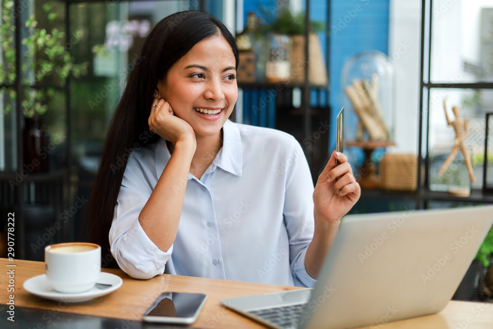 Asian woman using credit card shopping online in coffee shop cafe Asian woman using credit card shopping online in coffee shop cafe