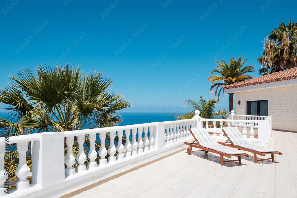 sunny terrace with sun beds, ocean view house with palm trees