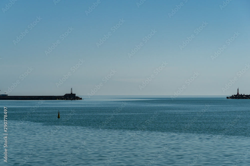 View from shore to water area of seaport. From open sea, port's water area is limited by  Breakwaters. Light pointers are installed on extreme parts of breakwaters. Calm Black Sea to very horizon.