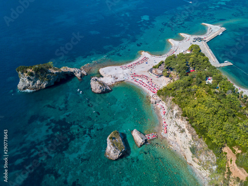 Aerial view of Sveti Nicola, Budva island, Montenegro. Hawaii beach, umbrellas and bathers and crystal clear waters. Jagged coasts