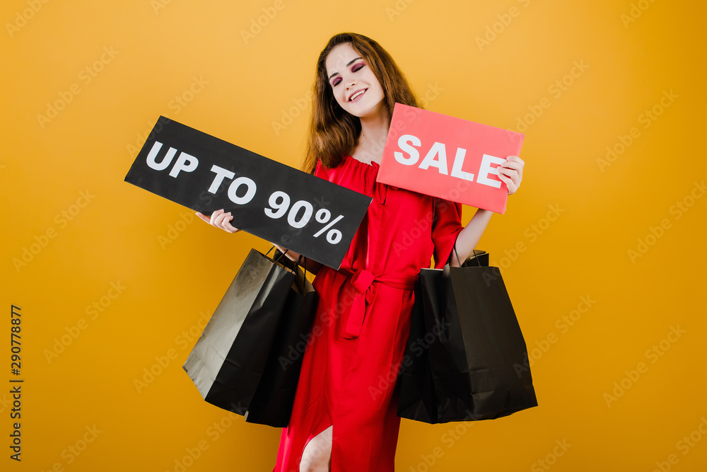 smiling girl has sale up to 90% sign with paper shopping bags isolated over yellow smiling girl has sale up to 90% sign with paper shopping bags isolated over yellow