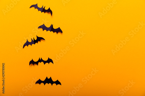Witch on broom and black paper bats flying on yellow background. Halloween concept. Paper cut style. Top view