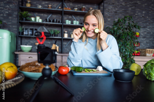 Young beautiful blonde takes on videos as she cooks in the kitchen © teksomolika