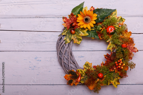 Door wreath made of artificial flowers and autumn plants on shabi white wooden background. photo