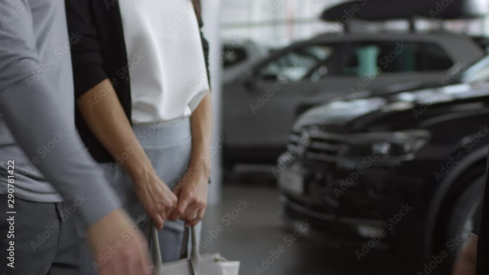 Close up shot of salesman giving handshake to male customer standing with wife in car showroom Close up shot of salesman giving handshake to male customer standing with wife in car showroom
