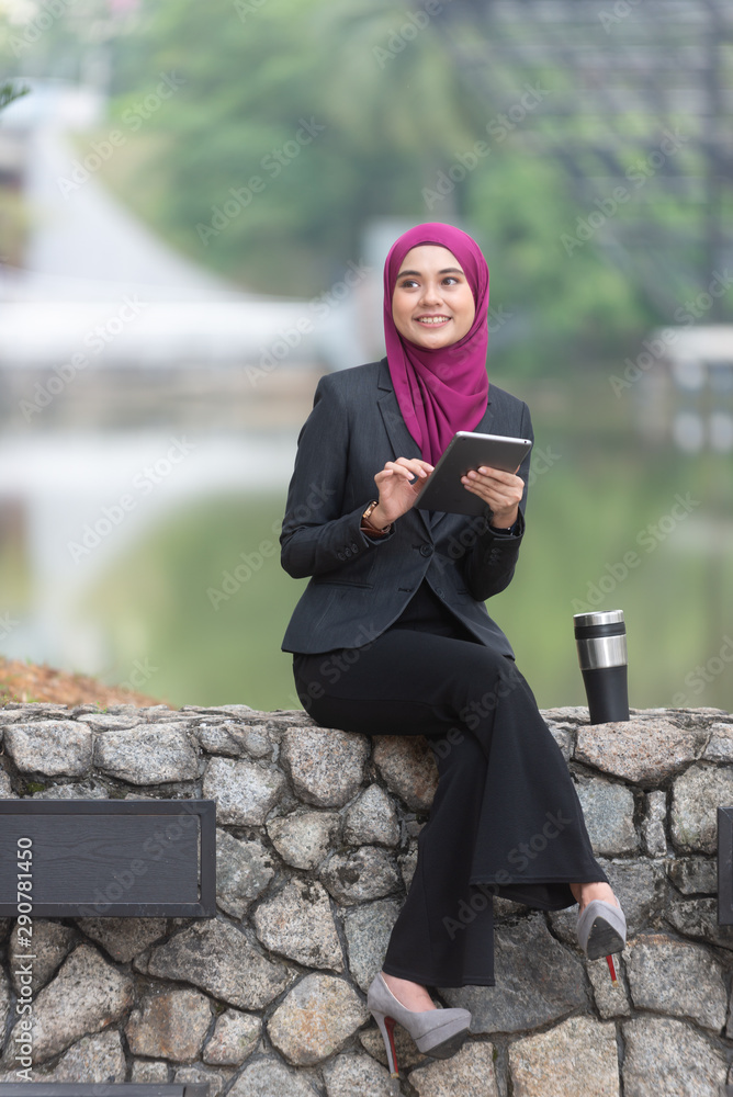 Obraz premium Muslim Businesswoman with her tablet and her coffee at the park.