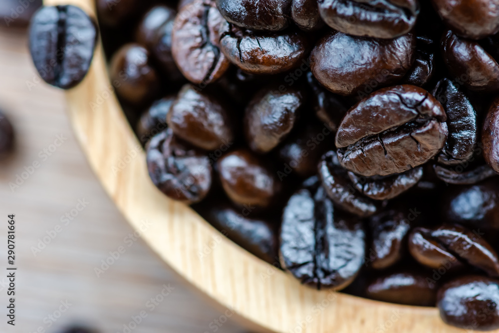 Obraz premium Roasted coffee beans until the coffee beans are black, placed in a wooden bowl.