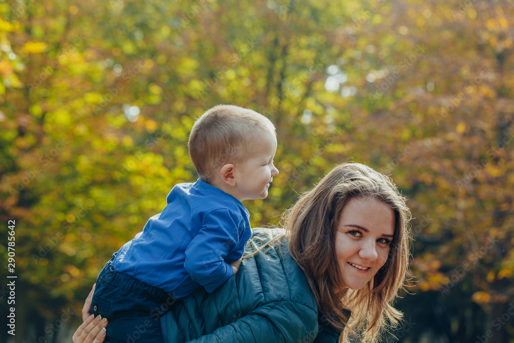 portrait of a beautiful young mother with her son walks in the autumn park. portrait of a beautiful young mother with her son walks in the autumn park.