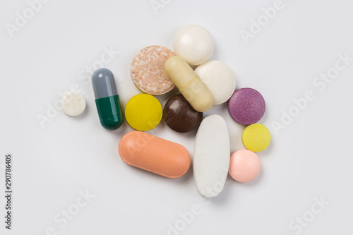 Assorted pharmaceutical medicine pills, tablets and capsules.Heap of assorted various medicine tablets and pills different colors on white background. Top view.Copy space