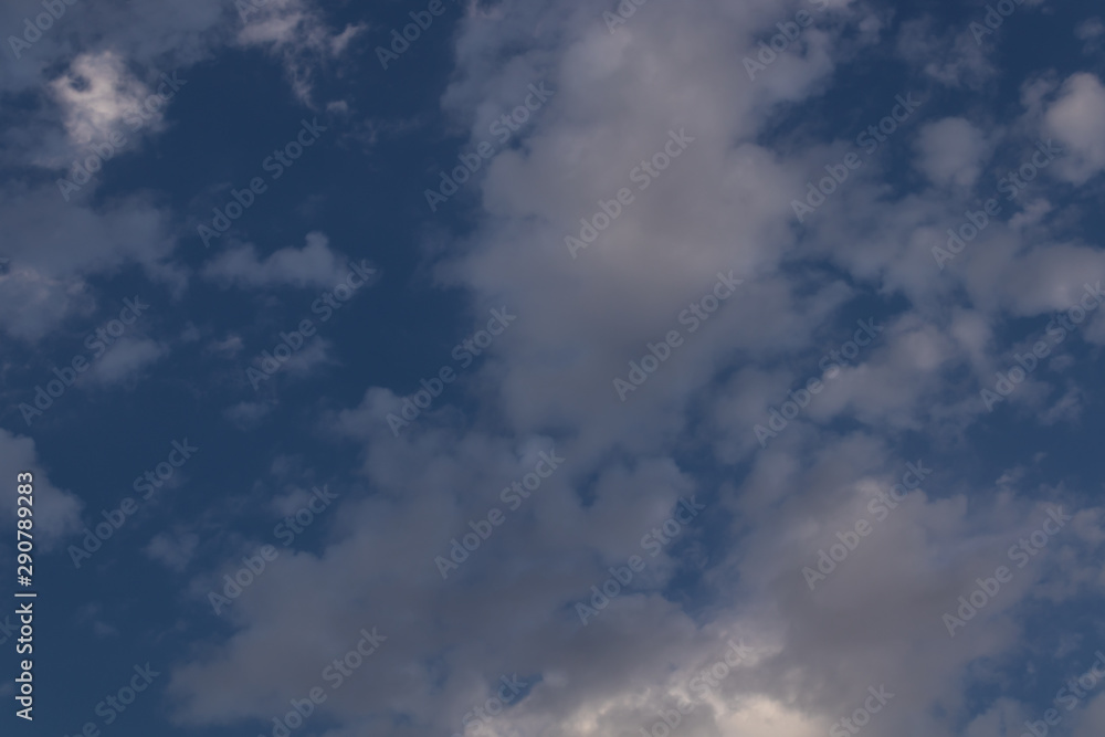 gray clouds against a blue sky through which the sun's rays are trying to break through gray clouds against a blue sky through which the sun's rays are trying to break through