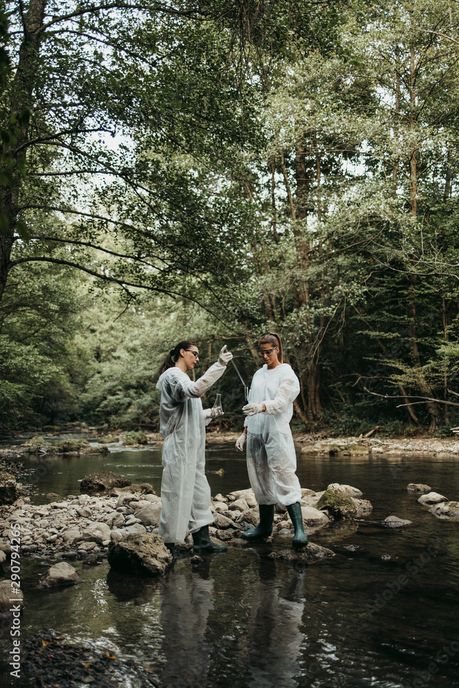 Scientists biologists and researchers in protective suits taking water samples from polluted river. Scientists biologists and researchers in protective suits taking water samples from polluted river.