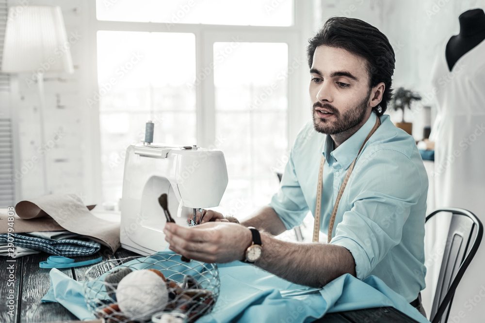 Attentive brunette bearded man looking at thread