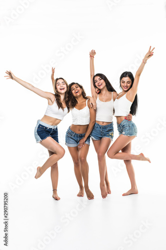 Full length portrait of a happy four girls pointing fingers on a white background