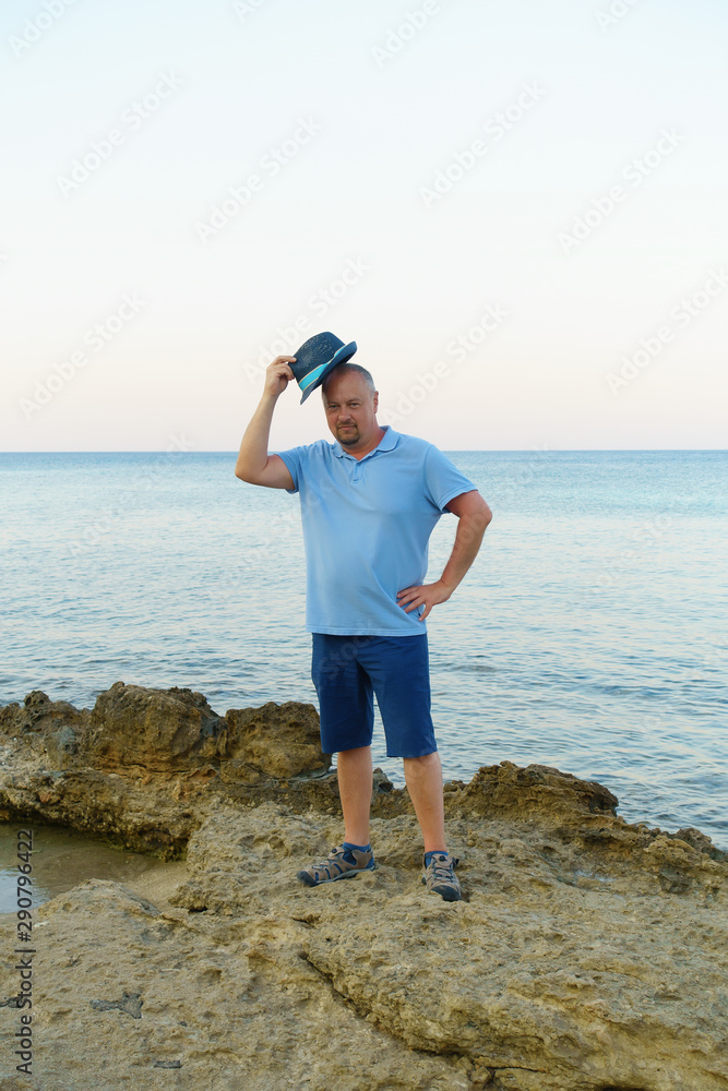 young man in hat posing on the seashore
