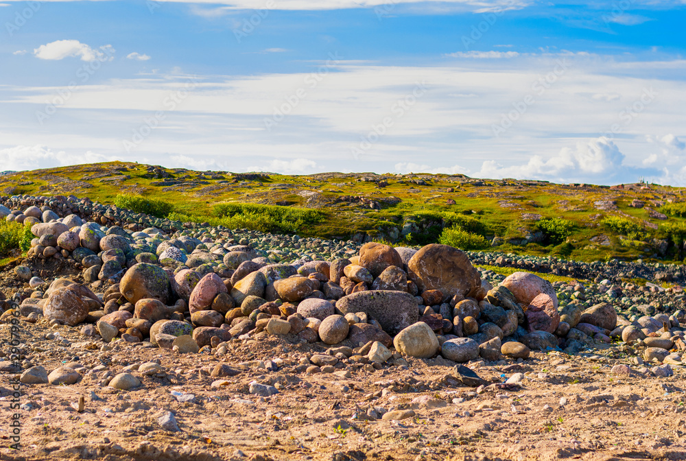 A handful of huge stones surrounded by grass. Bright sky in the clouds. Hills in the background. A handful of huge stones surrounded by grass. Bright sky in the clouds. Hills in the background.