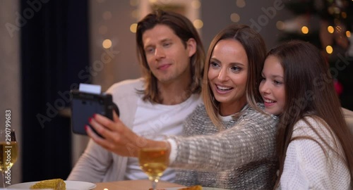 Beautiful family celebrating Christmas at home and taking instant pictures