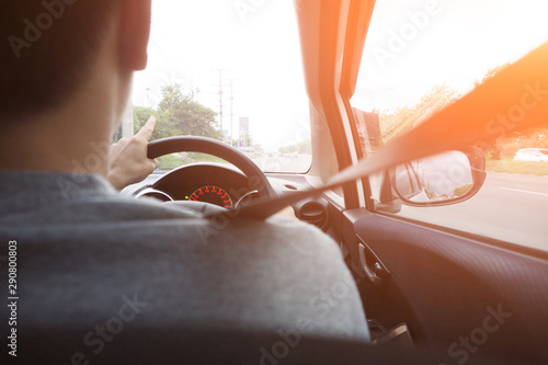Back side of man driving on the road holding steering wheel steady using low gear and slow speed to avoid accidents Transportation safety driving carefully lifestyle and traffic concept