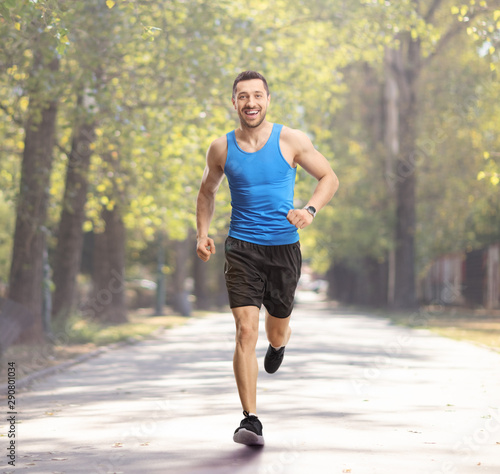 Young guy jogging in a park and smiling