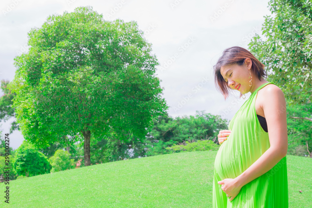 Happy pregnant woman relaxing outside in the park outdoor