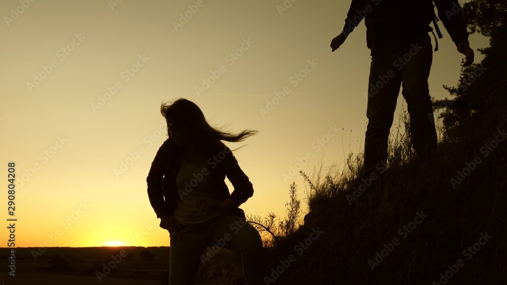 male traveler and female traveler descend from top of the hill. teamwork of business people. tourists descend from the mountain in the sunset, one after another. Happy family on vacation.