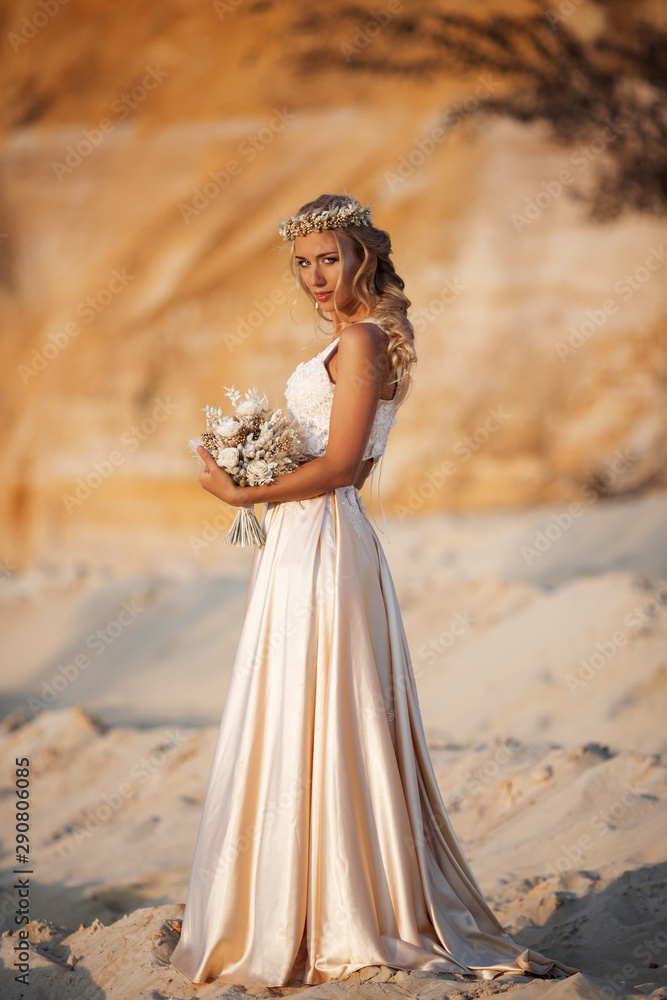 Beautiful bride is wearing fashion flying dress and wreath in the great desert in Dubai.