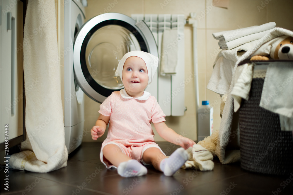 a small child near the washing machine looks away a small child near the washing machine looks away