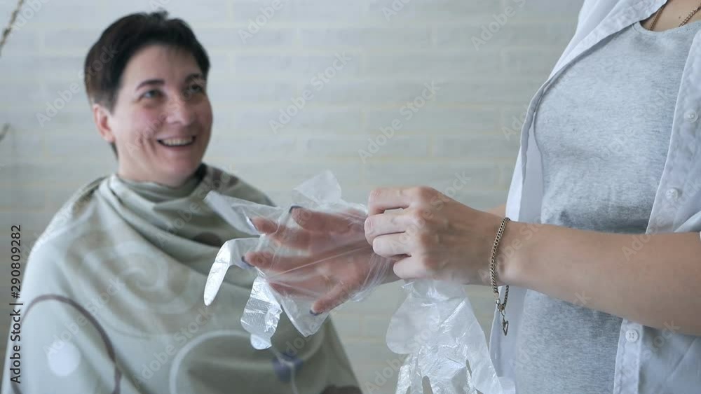 The girl puts on cellophane gloves. Hair dye The girl puts on cellophane gloves. Hair dye