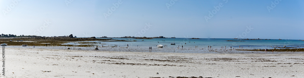 panorama view of idyllic and wild beach at low tide with people swimming and relaxing
