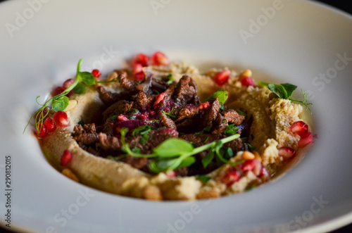 lebanese hummus dish with fresh vegetables, beef meat & pomegranate seeds