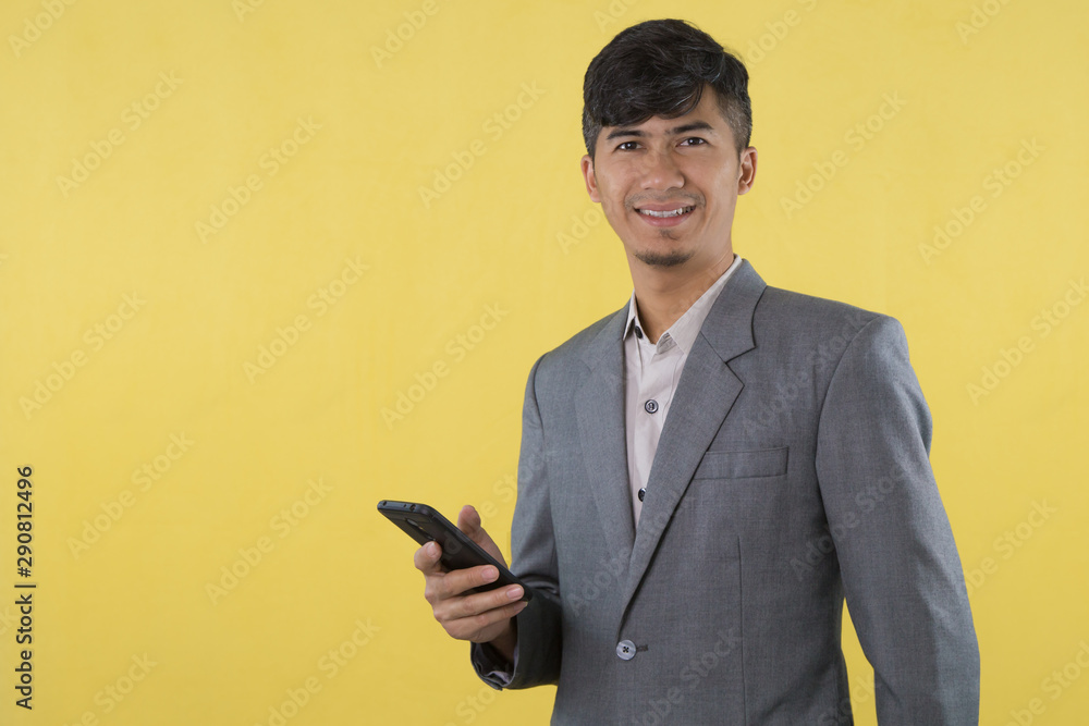 Handsome young Business Asian man using mobile phone isolated on Yellow background. Handsome young Business Asian man using mobile phone isolated on Yellow background.