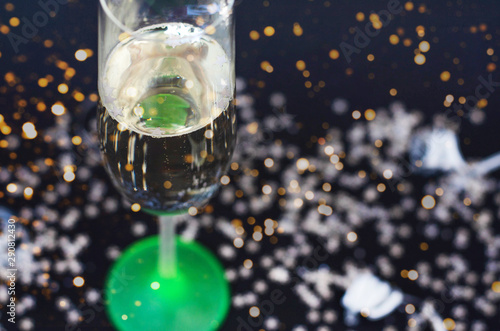 Neon glass with champagne on a black background with silver confetti.