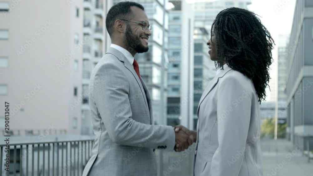 Smiling man and woman shaking hands on street. Cheerful African American colleagues meeting outdoor. Business handshake concept Smiling man and woman shaking hands on street. Cheerful African American colleagues meeting outdoor. Business handshake concept
