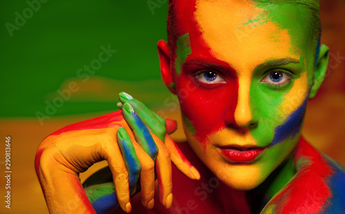 Portrait of the bright beautiful young woman with face art and body art. Contrast colors in creative make-up photo