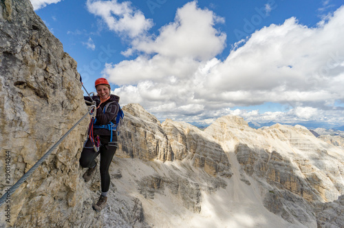 attractive blonde female mountain climber on a steep Via Ferrata in the Italian Dolomites