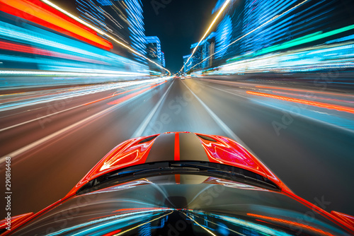 View from roof of the red muscle car Car moving in a night city, Blured road with lights with car on high speed. Concept rapid rhythm of a modern city.