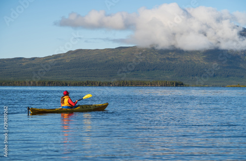 A woman kayaking on a lake in the wilderness. Jamtland, Sweden.