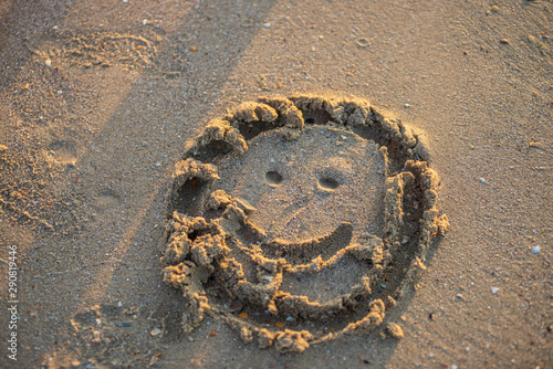 view on happy smiley face drawing on a sand.