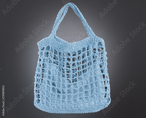 Handmade sky blue string bag on a gray background. Close-up.