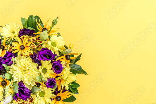 Stylish colorful beautiful spring bouquet isolated on light yellow background. Bright fresh purple and yellow flowers. Decorative composition greeting card for the holiday on the birthday. Copy space
