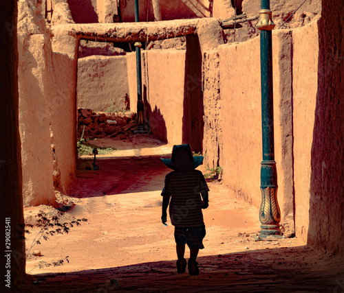 Young boy walking in the old alley of a damage mud house.