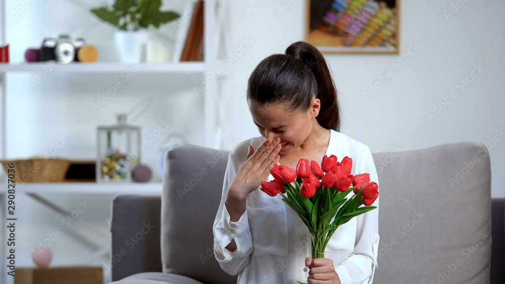 Young woman holding bunch of tulips and sneezing, seasonal allergy, health Young woman holding bunch of tulips and sneezing, seasonal allergy, health